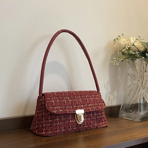 Elegante borsa a tracolla in tweed rosso con finiture dorate su tavolo di legno