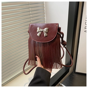 Detail of burgundy tassel crossbody bag with metallic bow and faux leather texture