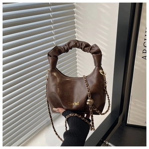 Détail de la poignée plissée marron et du logo doré sur ce sac à bandoulière chaîne