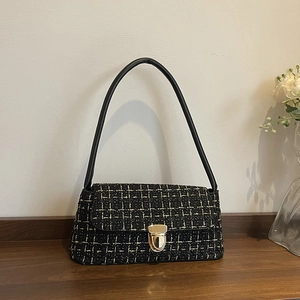 Elegante borsa a spalla in tweed nero con chiusura dorata su piano in legno