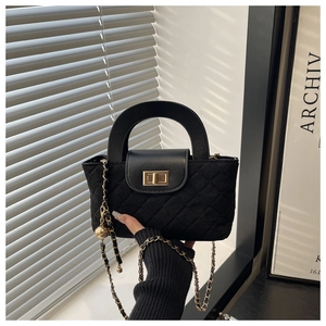 Close-up of black quilted velvet bucket bag with gold clasp and chain strap detail