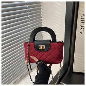 Close-up of burgundy quilted texture with black leather flap and gold sphere chain strap