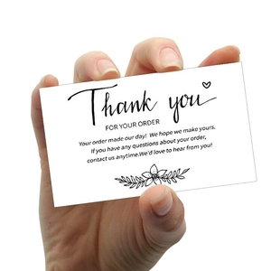 Cartes de remerciement minimalistes blanches tenues à la main sur fond blanc épuré
