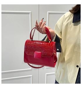 Detail of red crossbody bag featuring crocodile pattern flap and square buckle closure