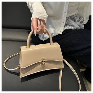 Gros plan du sac à main trapèze beige minimaliste avec détail de fermoir annulaire doré