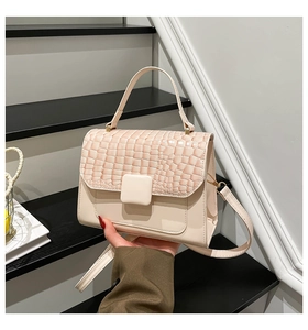 Detailed close-up of a cream and pink alligator pattern handbag with large square buckle