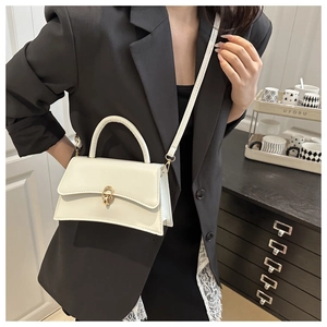 White minimalist crossbody bag with gold twist lock shown in a lifestyle setting