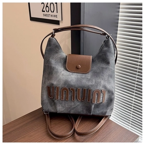 Detail of gray vintage canvas bag with brown leather flap and UIUIVINIU letter print