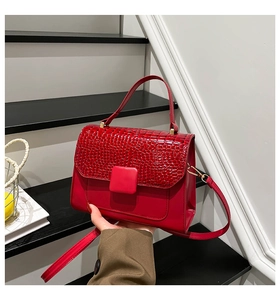 Detailed view of red crocodile embossed leather handbag with golden hardware