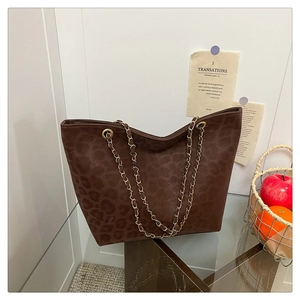 Close-up of leopard print texture and gold chain strap on dark brown tote bag