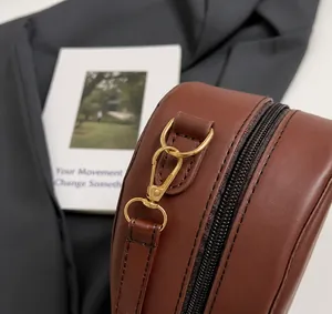 Close-up of golden metal hook and black zipper on brown textured leather shoulder bag