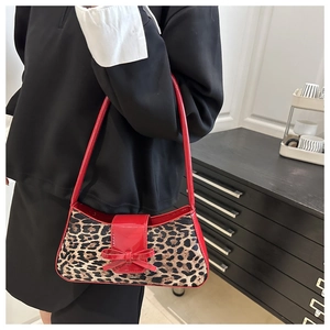 Détail d'un sac rétro imprimé léopard avec bandoulière en cuir verni rouge et noeud