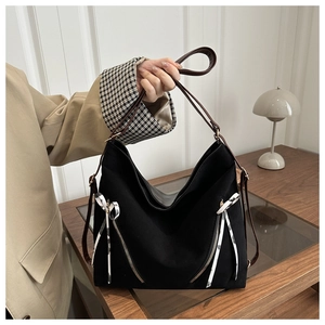 Détail du sac cabas noir avec fermetures éclair, rubans blancs et poignées marron