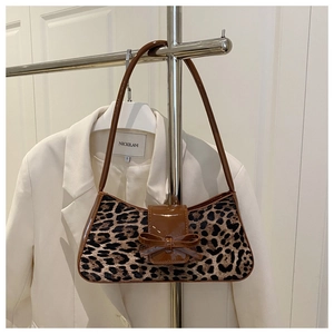 Close-up of leopard print baguette bag with brown patent leather handle and bow detail