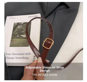 Detail view of adjustable dark brown leather shoulder strap with gold metal buckle