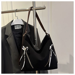 Détail du cabas en nylon noir avec fermetures éclair diagonales et nœud en ruban damier