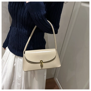 Detail view of cream beige shoulder bag with golden cylindrical metal twist lock buckle