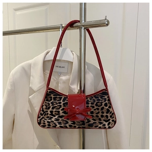Detail of leopard print underarm bag with red patent leather trim and a bow accent