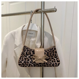 Detail of leopard print shoulder bag with bow decor and glossy trim on a white blazer