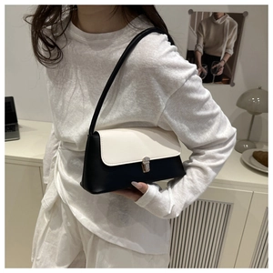 Detail of minimalist black and white underarm bag with square metal buckle on a model