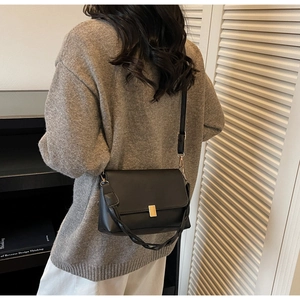 Dettaglio borsa a tracolla vintage in pelle nera con manico intrecciato e fibbia dorata