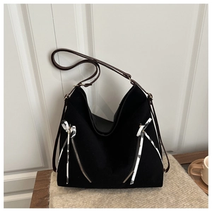 Close-up of large black tote bag featuring decorative zippers and striped ribbon detail