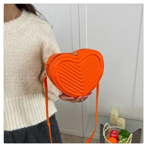 Vibrant orange heart-shaped crossbody bag with V-quilted texture and gold hardware details