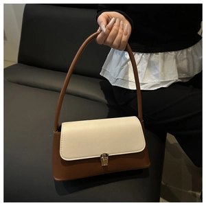 Détail du sac bicolore en similicuir avec boucle dorée et longue poignée cylindrique