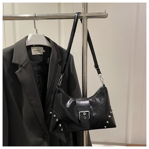 Detail of black punk leather tote bag with silver conical studs and metal buckle strap