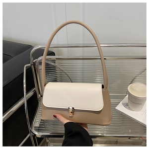 Detail of a chic two-tone beige shoulder bag featuring a gold metal buckle and long strap