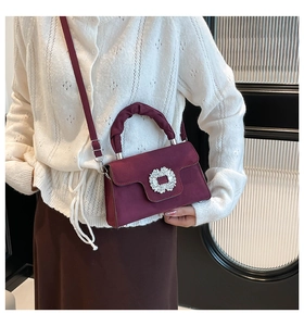 Detail of burgundy suede handbag with silver rhinestone buckle and pleated handle
