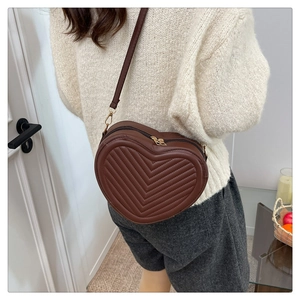Detail of dark brown heart-shaped crossbody bag with V-quilted faux leather finish