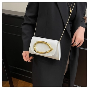Close-up of a white patent leather crossbody bag with a large gold ring buckle decoration
