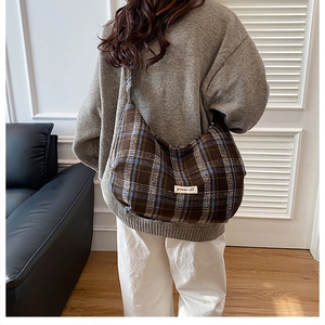 Close-up of retro plaid hobo bag featuring power off patch and wide shoulder strap