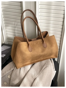 Close-up of large brown suede tote bag with leather handles on a minimal background