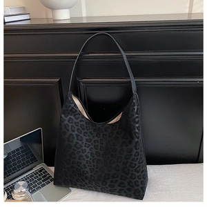 Close-up of a large black leopard print hobo tote bag in a professional office setting