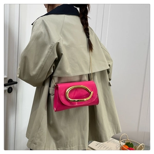 Detail of rose pink patent leather crossbody bag with oversized gold chain buckle