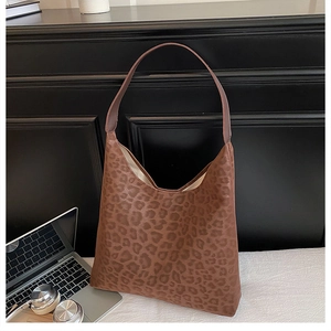 Close-up of leopard print shoulder bag with detailed animal texture on wood desk