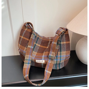 Detailed view of the plaid fabric texture and adjustable strap on the crossbody bag