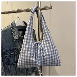 Detail of blue and white checkered canvas tote bag with knot strap hanging naturally