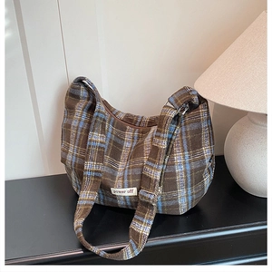 Detailed view of brown and blue plaid wool tote with 'power off' woven label