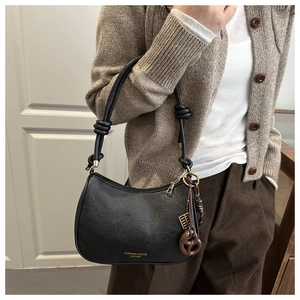 Détail du sac sous l'aisselle en cuir grainé noir avec sangle à nœuds et lettrage