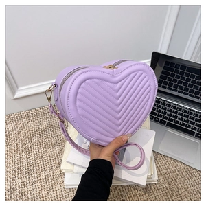 Close-up of heart-shaped purple crossbody bag with quilted V-pattern and gold hardware