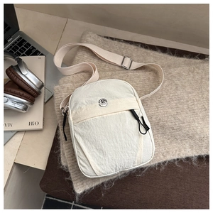 Detail of cream nylon mini crossbody bag with round metal logo and adjustable strap