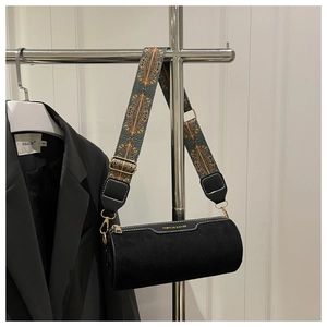 Detail of black cylinder bag featuring ethnic embroidery strap and white contrast stitching