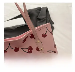 Détail d'un sac cabas rose à imprimé cerise avec longues anses et rivets dorés