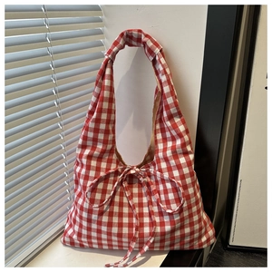 Detail of red and white checkered tote bag with a decorative bow in casual retro style
