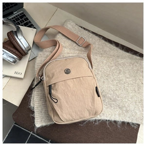 Macro detail of khaki nylon phone bag with metal M logo and front zipper pocket