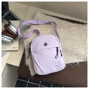 Detail of lavender nylon shoulder bag showing zip front pocket and metallic round logo