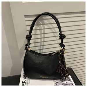 Close-up of black leather underarm bag featuring knotted strap and vintage tassel detail